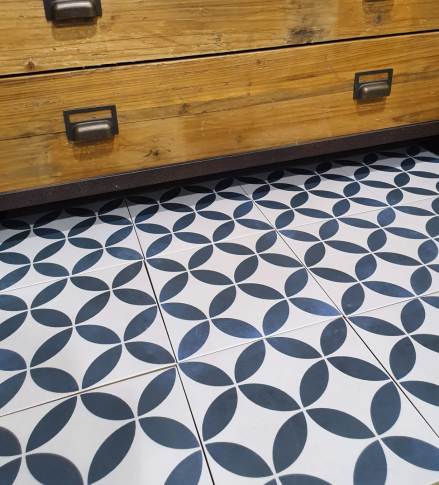 Navy and white geometric petal pattern floor tiles under a timber cabinet