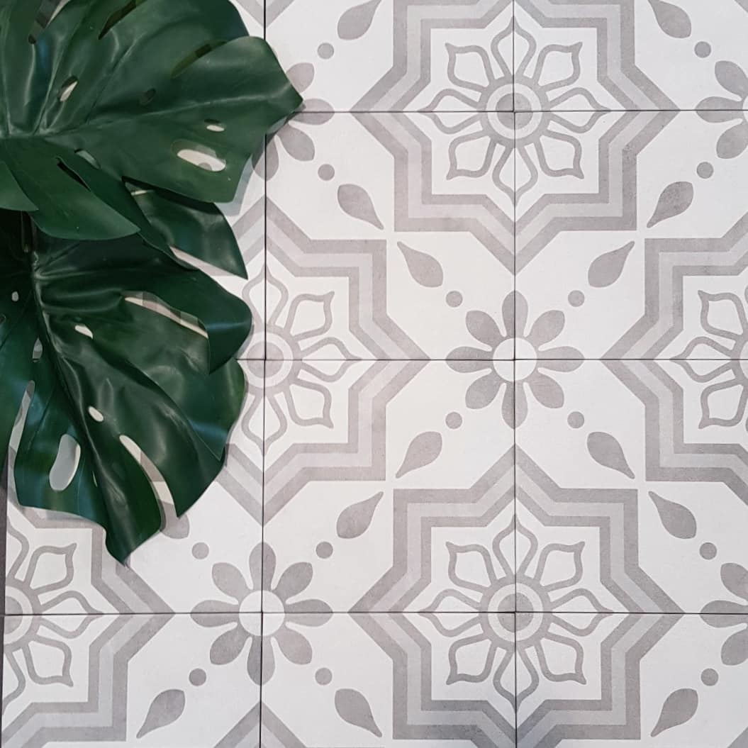 Close up of KC852 grey and white star and flower pattern floor tiles with a monstera leaf