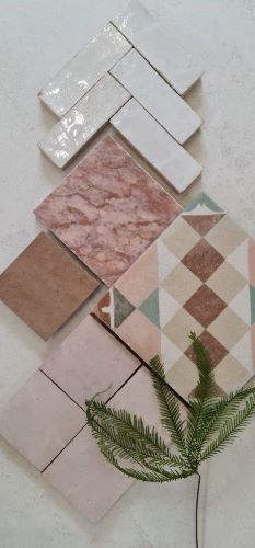 Flat lay of KC967 pattern tile with white herringbone wall tiles, pink marble and plain pink tiles and a fern frond