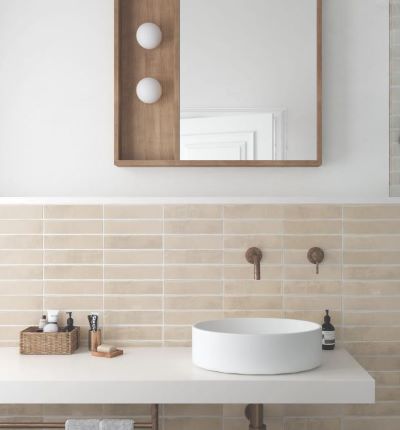 Bathroom splashback of pale sand coloured narrow wall tiles with a round basin and timber mirror